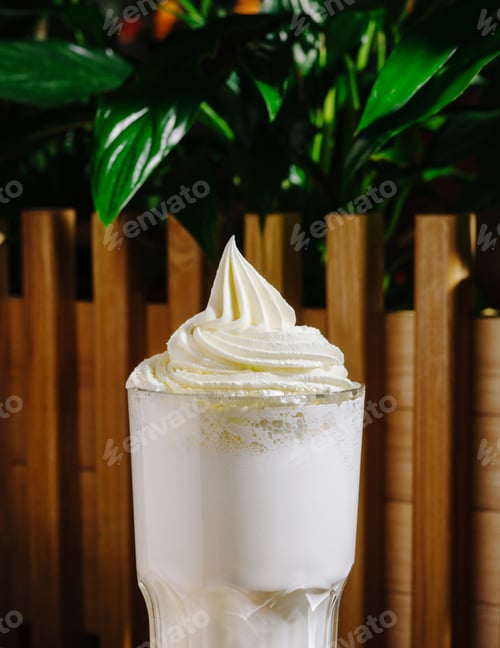 Preview: Whipped cream topped drink served in a glass against a green backdrop