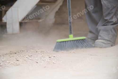 Preview: Unrecognizable young builder sweeping the floor at a construction site.