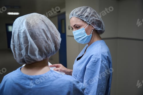 Preview: Female doctors in protective masks and uniform talking in the hall in clinic