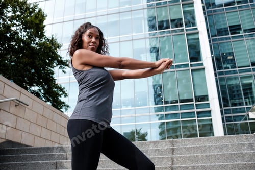 Preview: Fitness mature black woman stretching in business environment.