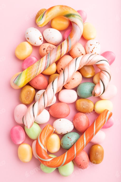 Preview: Various caramel candies on pink background. close up, top view