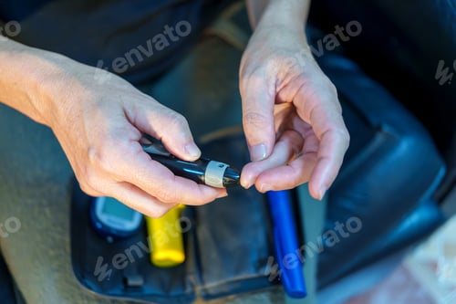 Preview: Close up of hands using a lancet device to prick a finger for a blood sugar test