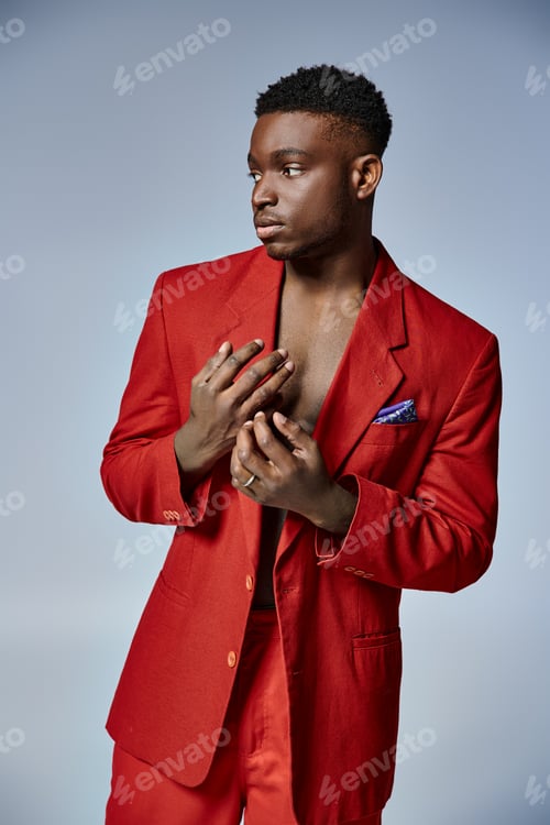 Preview: attractive young african american man in stylish red suit posing on gray backdrop, fashion concept