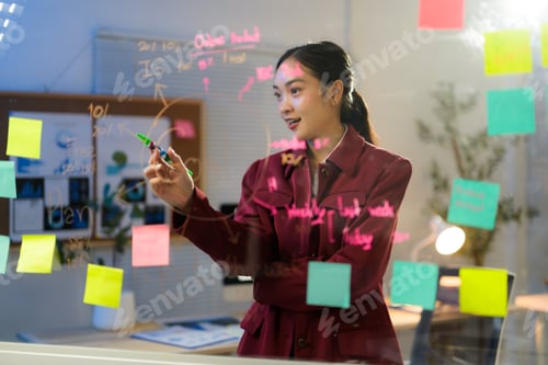 Preview: Young professional drawing project plan on transparent board with colorful sticky notes in office