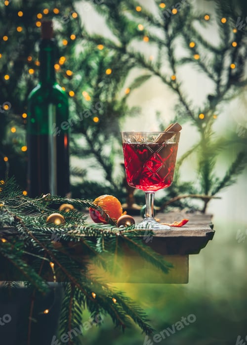 Preview: Glass of mulled wine with pine branches and fairy lights on background