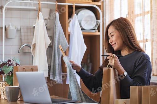 Preview: A female using laptop computer for selling clothes online or review product on social media at home