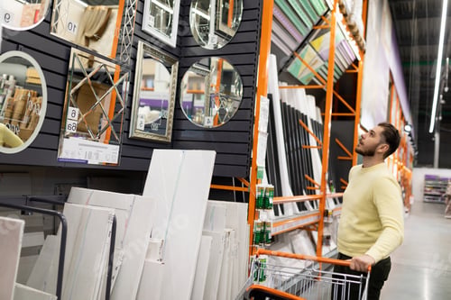 Preview: A customer chooses a new wall mirror for their home Next to a sample display in a hardware store