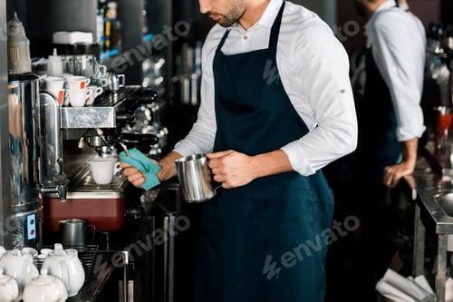 Preview: cropped view of barman in apron preparing coffee with coffee machine