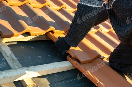 Preview: Closeup of worker hands installing yellow ceramic roofing tiles mounted