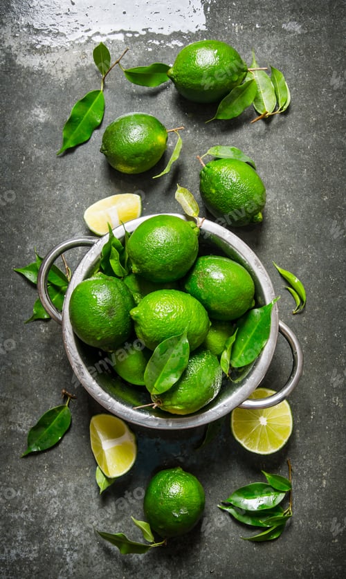 Preview: Lime background. Fresh limes in a saucepan with slices and leaves around.