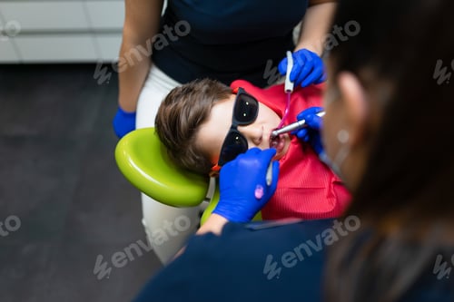 Preview: Dentist and assistant make preventive dental plaque cleaning for teenager