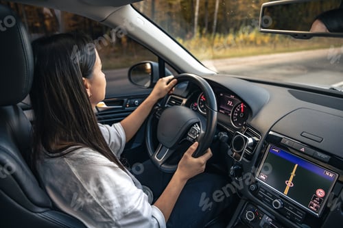 Preview: Attractive young woman driving a car, view from inside.