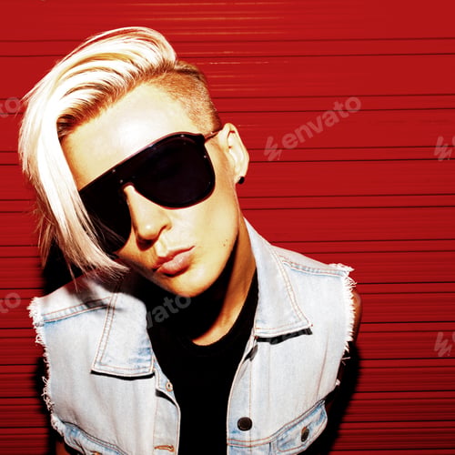 Preview: Girl with short hair in stylish clothes and sunglasses on a red