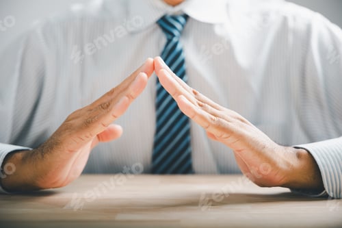 Preview: Close-up of hands forming a protective roof over a wooden table. The hands are male and wearing a