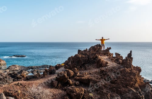 Preview: Tourist with open arms on a volcanic trail on the beach of Tacoron on El Hierro, Canary Islands
