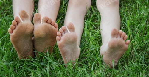 Preview: Children's legs on green grass. Selective focus.