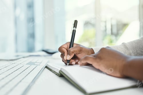 Preview: Cropped shot of an unrecognizable businesswoman writing in her notebook while sitting at her desk