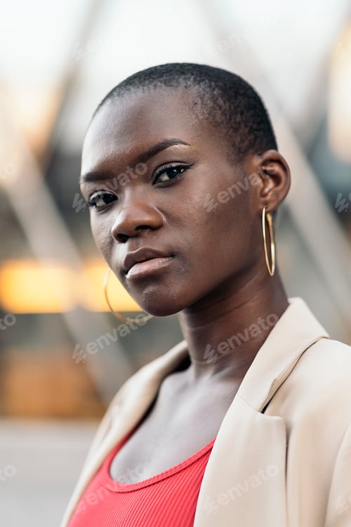 Preview: Portrait of a young woman with large earrings and short hair looking at camera