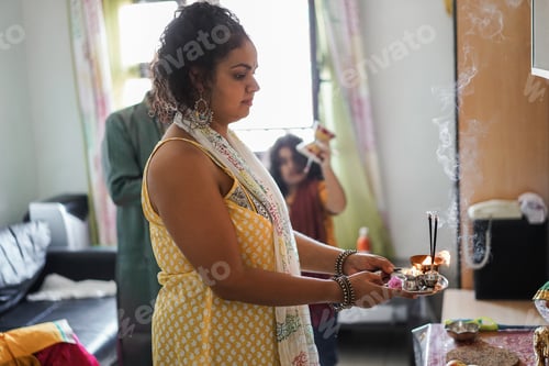 Preview: Indian family celebrating Diwali or hindu festival at home - Focus on mother hands holding offerings