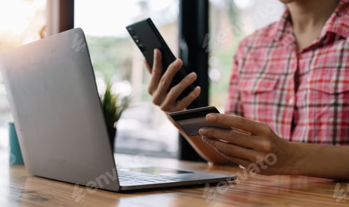 Preview: Close up young woman holding credit card and using mobile phone for online shopping. Online payment