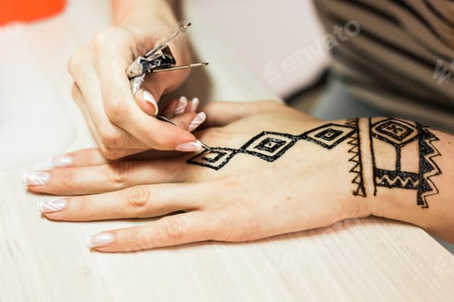 Preview: Artist applying henna tattoo on women hands. Mehndi is traditional Indian decorative art. Close-up