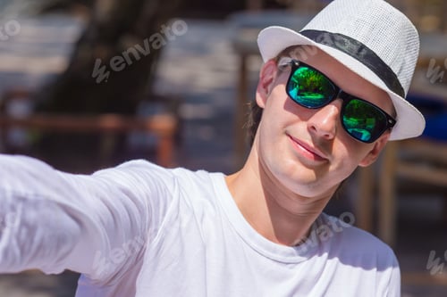 Preview: Young man making his selfie on beach at outdorr cafe