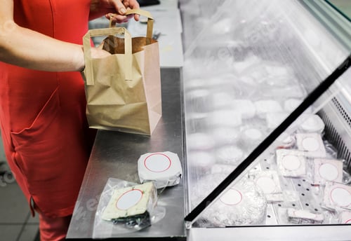 Preview: Sales clerk packing cheese into paper bag