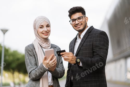 Preview: Two multiethnic business people conducting financial transactions online outdoors.