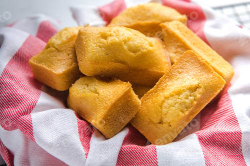 Preview: Close-up of corn muffins on plate with bowl of corn meal and additional muffins in the background.