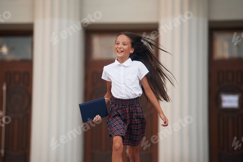Visualização: Fugindo da escola. Garota de uniforme está ao ar livre perto do prédio