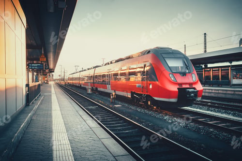 Vista previa: Beautiful railway station with modern red commuter train at suns