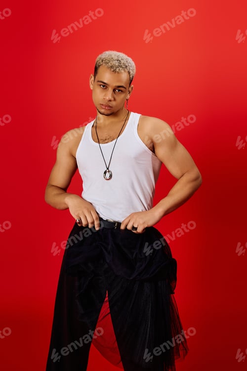 Preview: Stylish young man poses confidently in vibrant red studio showcasing modern fashion