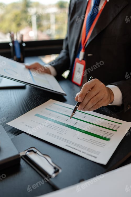 Preview: a businessman is reviewing accounting and financial statistics documents in his private office