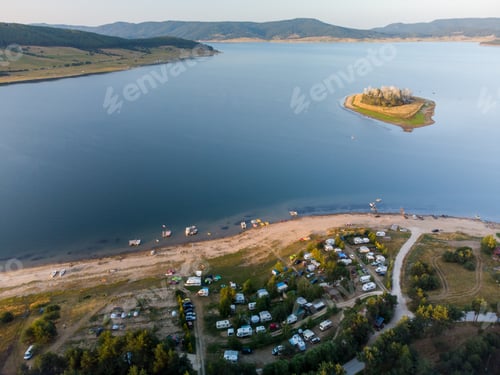 Preview: Aerial view of a campers van parked on a beach, mountain range landscape