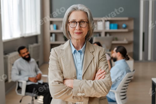 Preview: Confident senior businesswoman posing with arms crossed in modern office