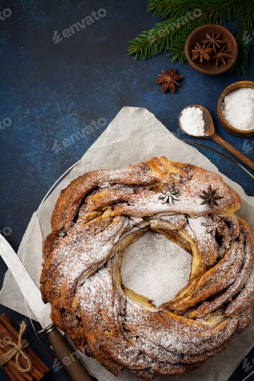 Preview: Christmas pie roll with cinnamon and powdered sugar on a dark old concrete or stone background. Sele