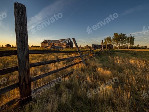 Preview: Rustic fence and barn at sunset in countryside.