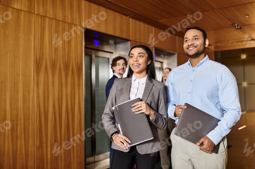 Business Professionals near Elevators, Holding Documents and Laptop