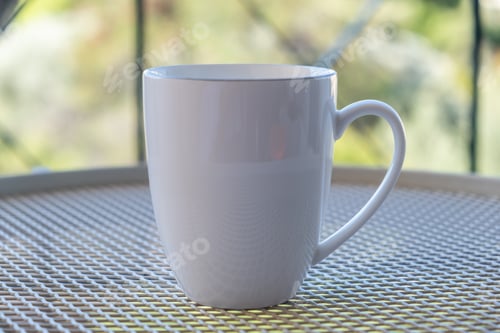 Preview: Placeit - Coffee cup mockup on a table, blur green background.