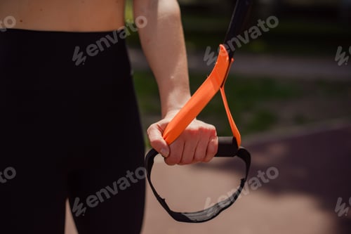 Preview: close up woman hand holding trx loop ready to training, workout outdoors