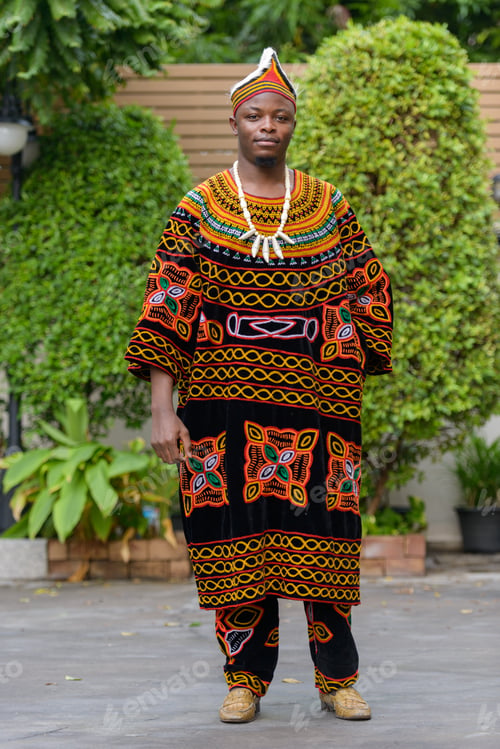Preview: Full body shot of young African man wearing traditional clothing outdoors