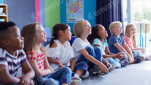 Preview: Group Of Smiling Elementary School Pupils Sitting On Floor In A Line Listening To Teacher