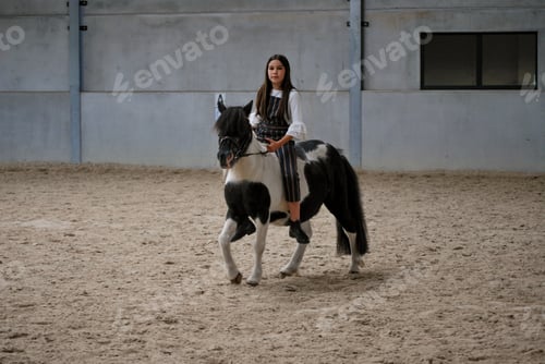 Preview: Generation Z girl horse-riding in a horse riding school in the countryside on her pony