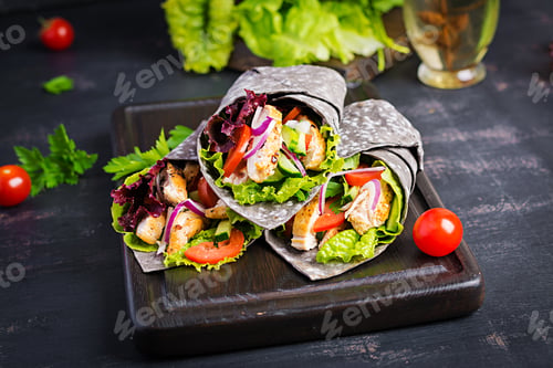 Preview: Tortilla with added ink cuttlefish wraps with chicken and vegetables on white background.
