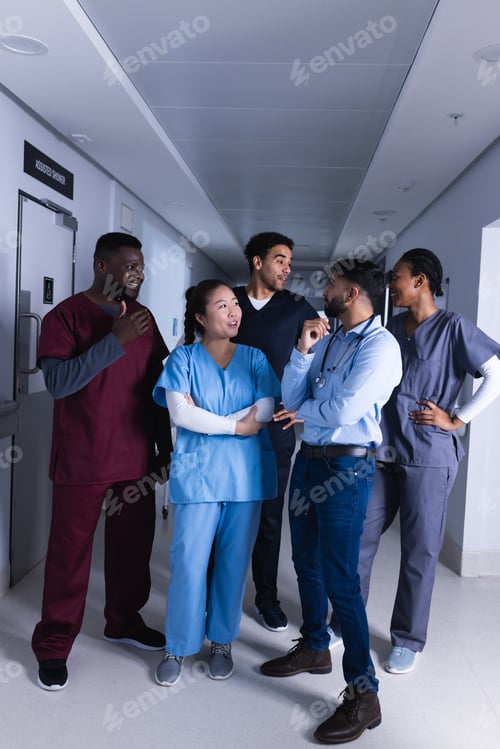 Preview: Happy diverse male and female doctors talking in hospital corridor
