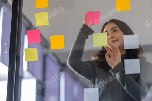 Preview: Business female employee with many conflicting priorities arranging sticky notes commenting and