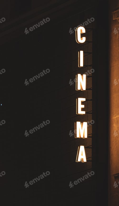 Preview: Illuminated cinema sign glowing brightly in the night, situated on the facade of a building.