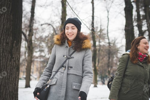 Preview: two young women standing in park with snow cover and smiling