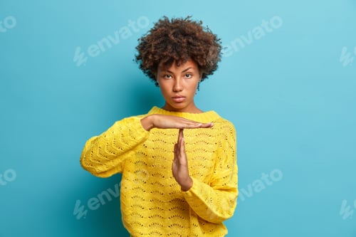Preview: Serious self confident curly haired Afro American woman makes timeout gesture demonstrates limit ask