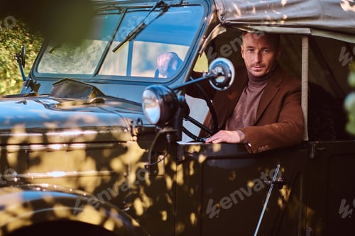 Preview: Handsome male elegantly dressed sit in the retro military machine.